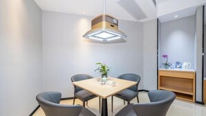A modern dining area with a table and four chairs, a pendant light, and a small plant on the table. - Guangyi Hotel (Quanzhou)