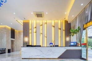 A hotel reception area with a marble counter, vertical light panels, and a computer monitor. - Guangyi Hotel (Quanzhou)