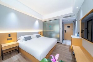 A modern hotel room with a bed, bedside table, and a large mirror. - Guangyi Hotel (Quanzhou)