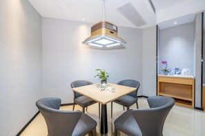 A modern dining area with a square table and four chairs, a pendant light, and a small plant on the table. - Guangyi Hotel (Quanzhou)