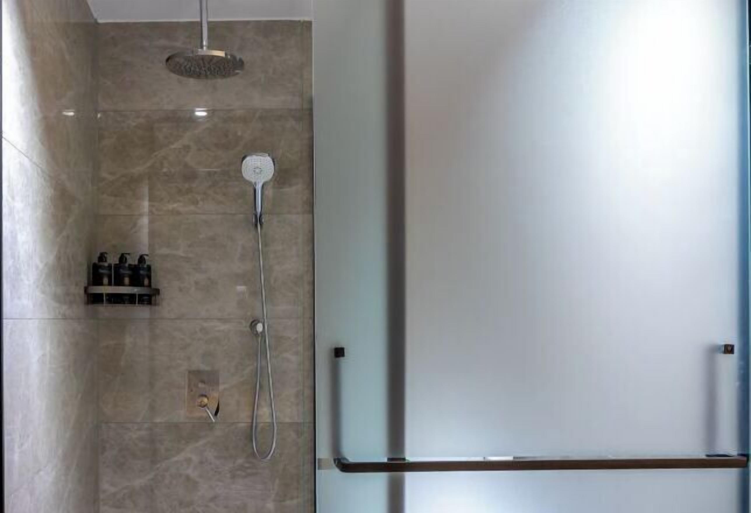 A modern shower with a handheld showerhead and a wall-mounted control.