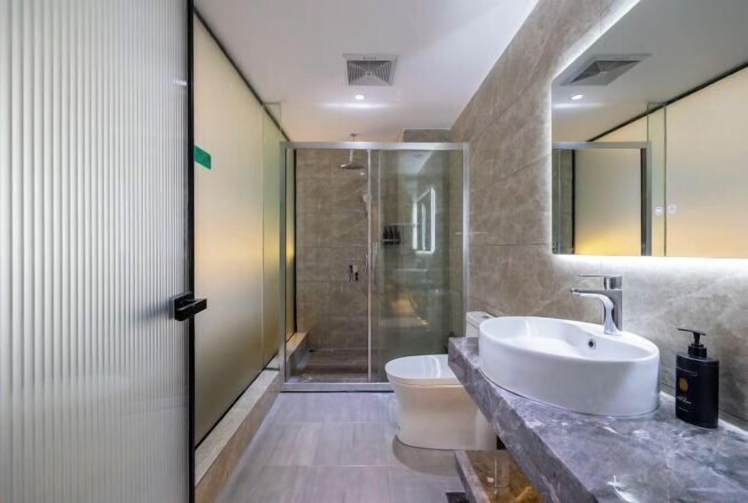 A modern bathroom with a glass-enclosed shower, a white sink, and a large mirror.