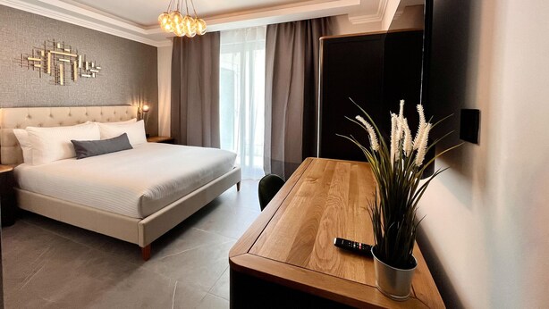 Una habitación de hotel moderna con una cama grande, un escritorio de madera, un televisor de pantalla plana y un adorno decorativo en la pared.