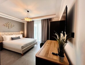 A modern hotel room with a large bed, a wooden desk, a flat-screen TV, and a decorative wall piece. - Sliema Studios (Sliema)