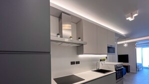 Una cocina moderna con armarios grises, encimera negra y horno integrado.