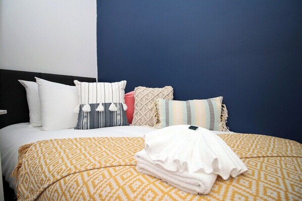 Cozy retreat with a plush bed, pillows, and a soft throw blanket.