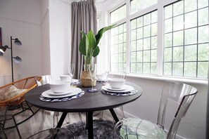 Enjoy meals in this stylish dining area with a round table for four, featuring a beautiful green plant centerpiece.