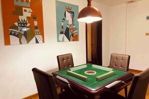 A dining area with a green table, four chairs, and two abstract paintings on the wall.