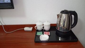 Una estación de café con una tetera, tazas y bolsitas de té sobre una bandeja.