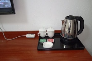 Un coin café avec une bouilloire, des tasses et des sachets de thé, le tout disposé sur un plateau.