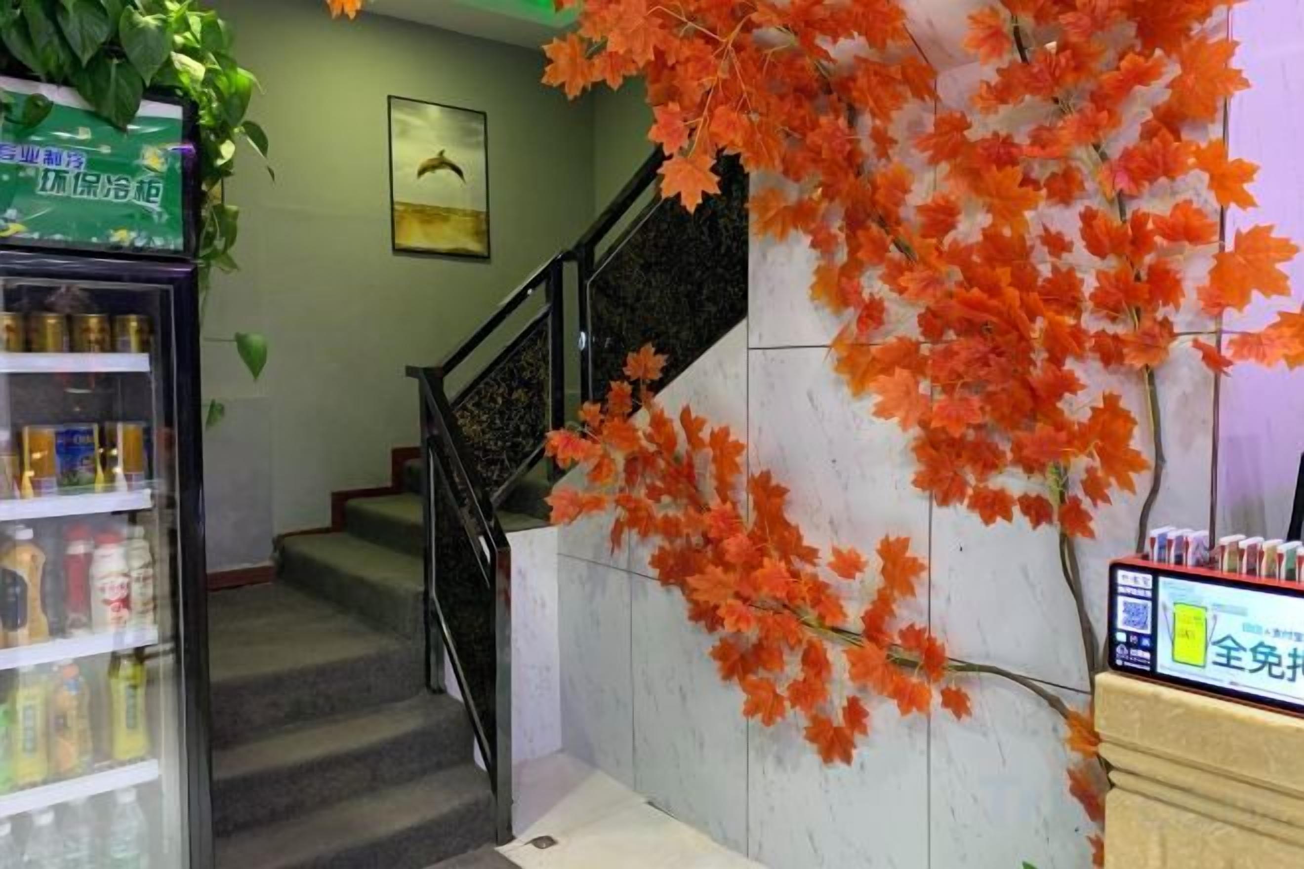 A staircase with a railing, a vending machine, and a wall with artificial foliage.