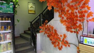 A staircase with a railing, a vending machine, and a wall with artificial foliage.