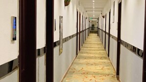 A long, narrow hotel corridor with patterned carpet, white walls, and doors on both sides. - Fu an Hotel (Guangzhou)