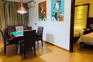 A hotel room with a dining area, two beds, and abstract art on the walls.