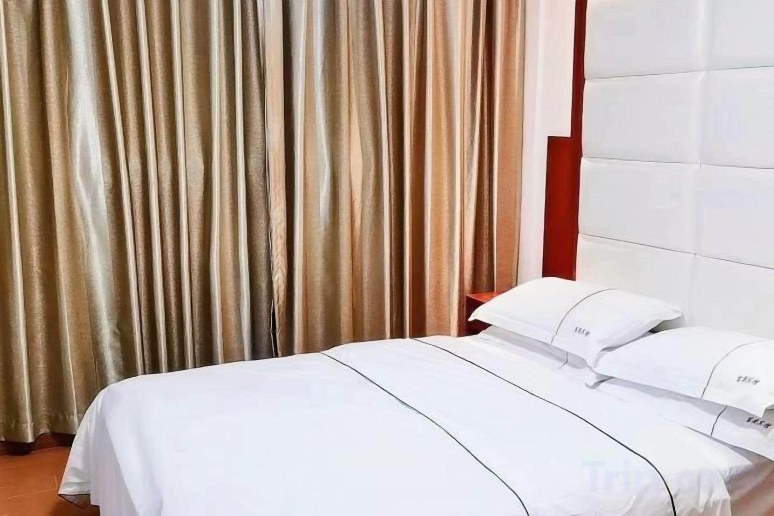 A hotel room with a bed, curtains, and a headboard.