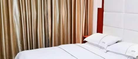 A hotel room with a bed, curtains, and a headboard.