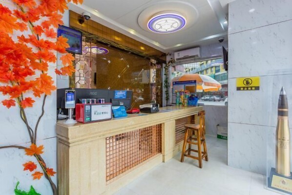 A reception desk with a digital screen, a cash register, and a small seating area.
