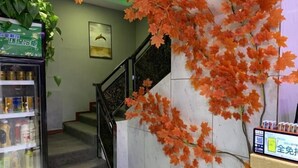 A staircase with a railing, a refrigerator with beverages, and a wall with artificial orange leaves. - Fu an Hotel (Guangzhou)