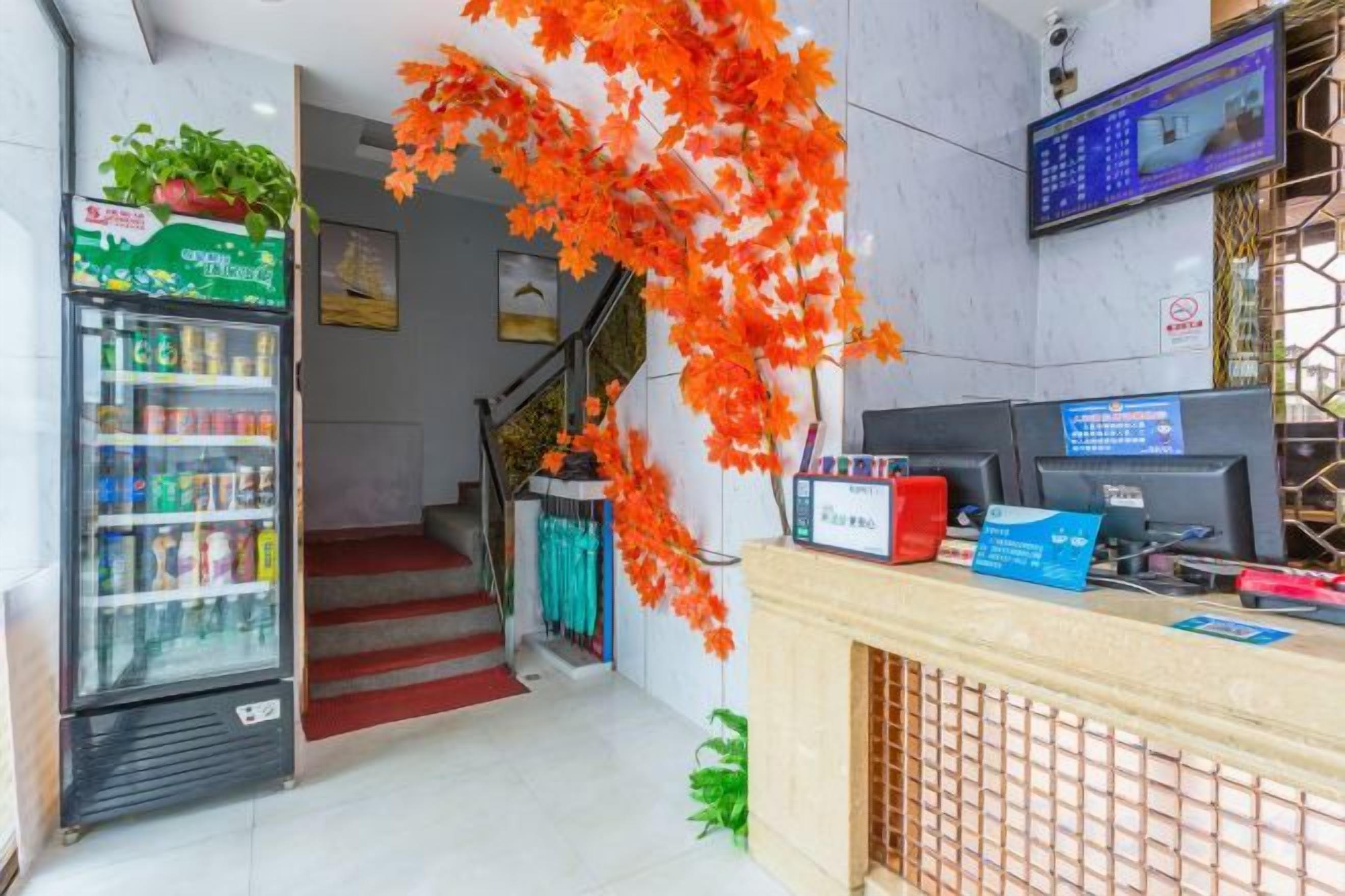 Zona de recepción de hotel con una escalera, una máquina expendedora y un mostrador con una computadora.