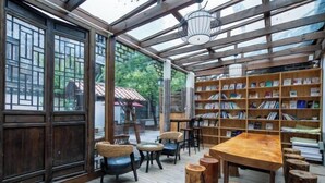 Een knus hoekje om te lezen, met houten boekenkasten, comfortabele zitmogelijkheden en een glazen afscheiding.