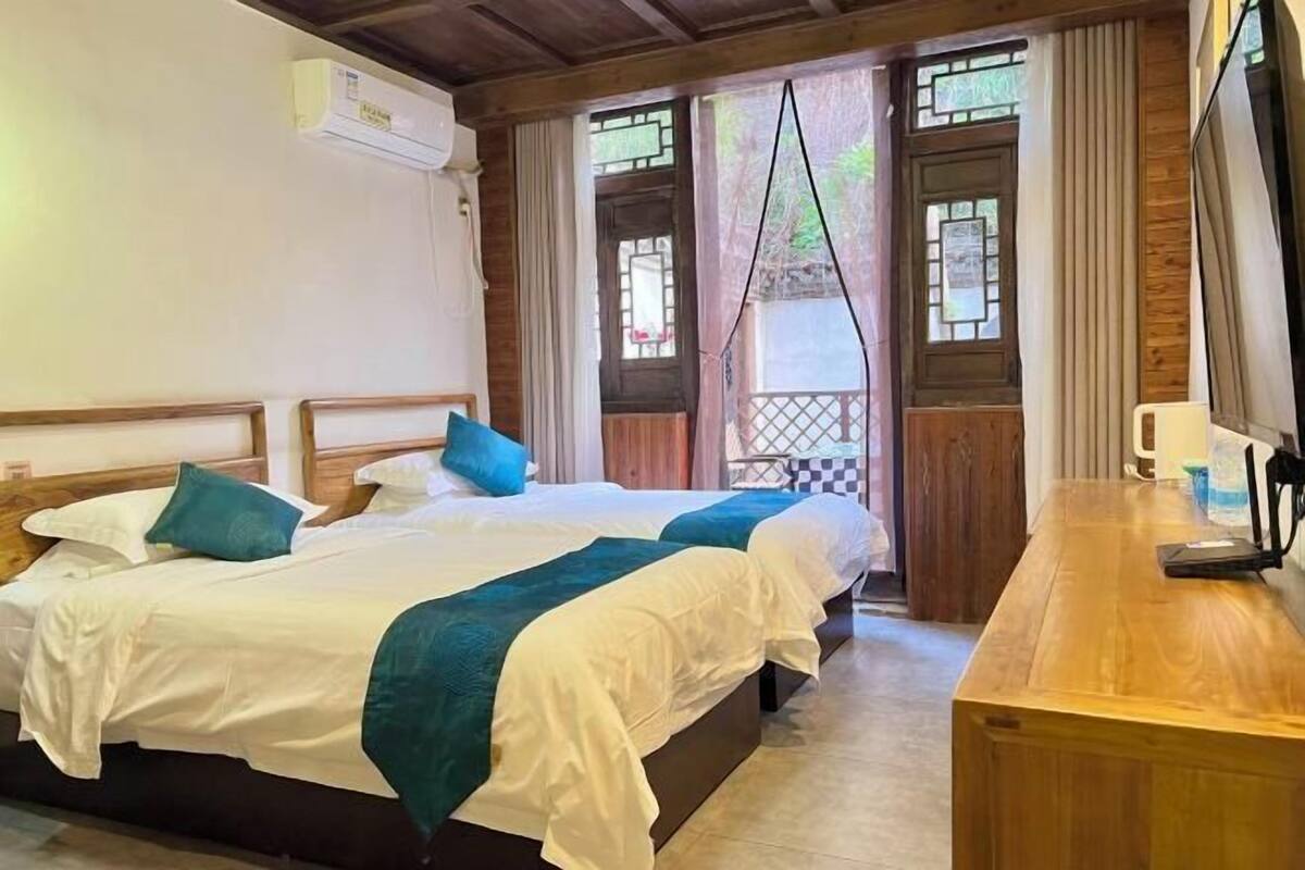 Een hotelkamer met twee bedden, een houten bureau en een televisie.