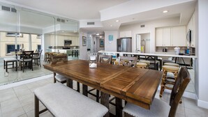 Uma sala de jantar espaçosa com uma grande mesa de madeira e bancos acolchoados, uma cozinha com eletrodomésticos modernos e amplas janelas com vista para a cidade.