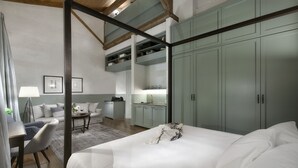 A modern bedroom with a large bed, a desk, and a chair. There is a kitchenette with a sink and a cabinet above it. - Athinaidos Avant Garde Loft by K&K (Αθήνα)