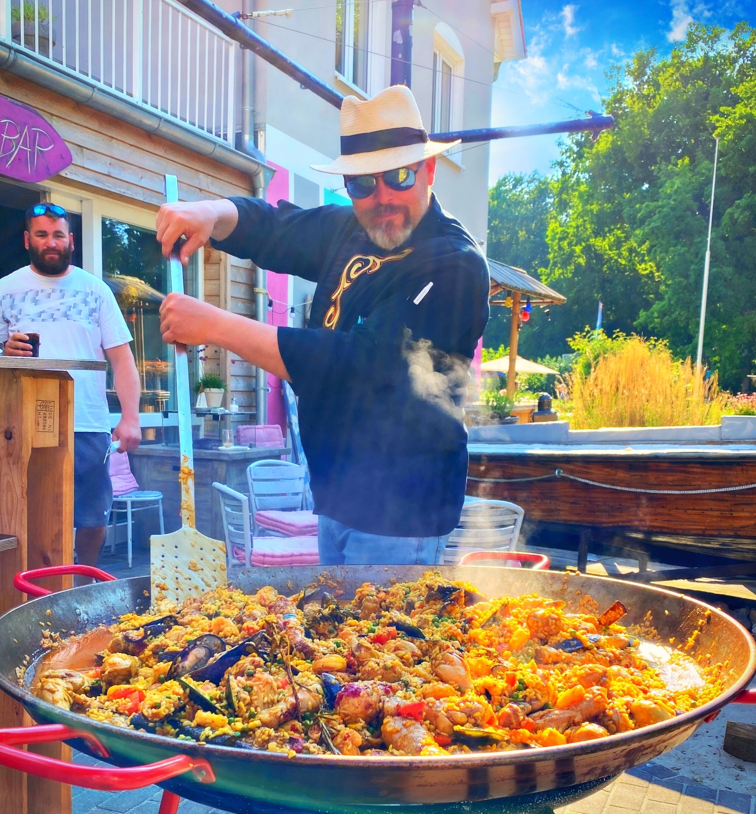 En person laver en stor portion paella udendørs.