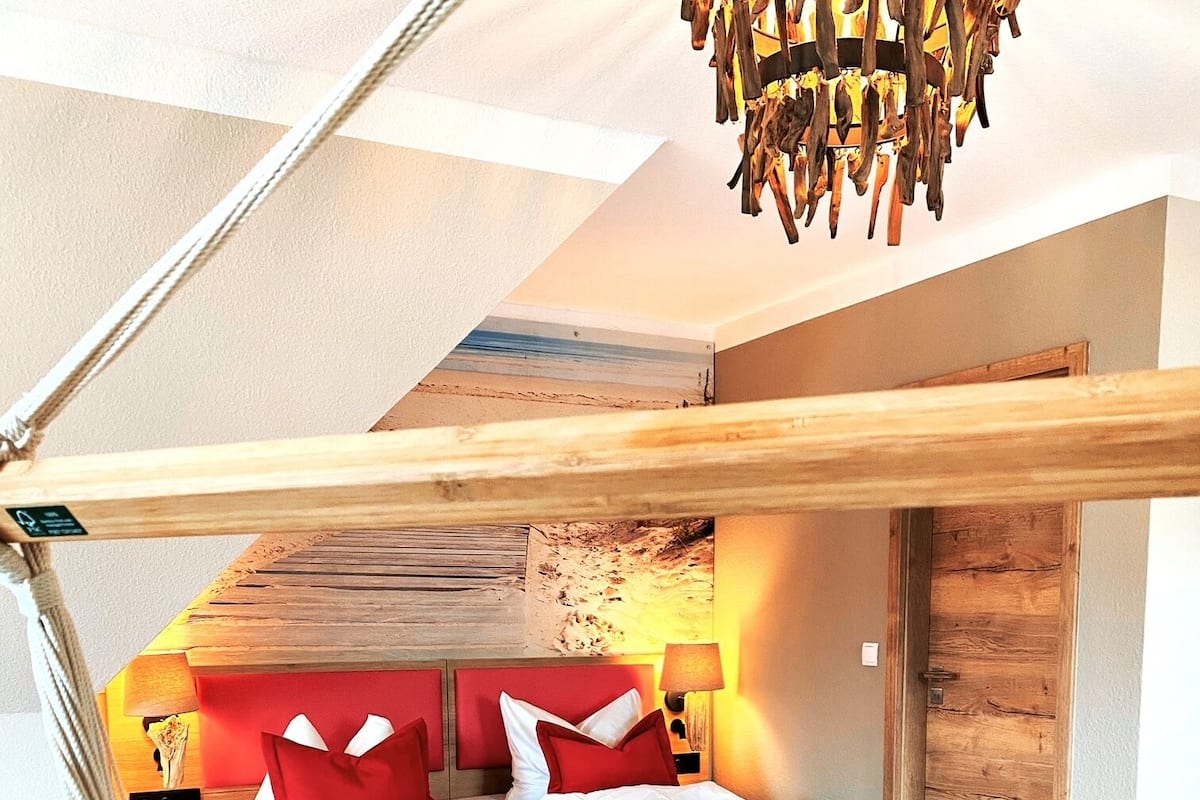Een moderne slaapkamer met een groot bed, een houten hoofdbord en een hanglamp.