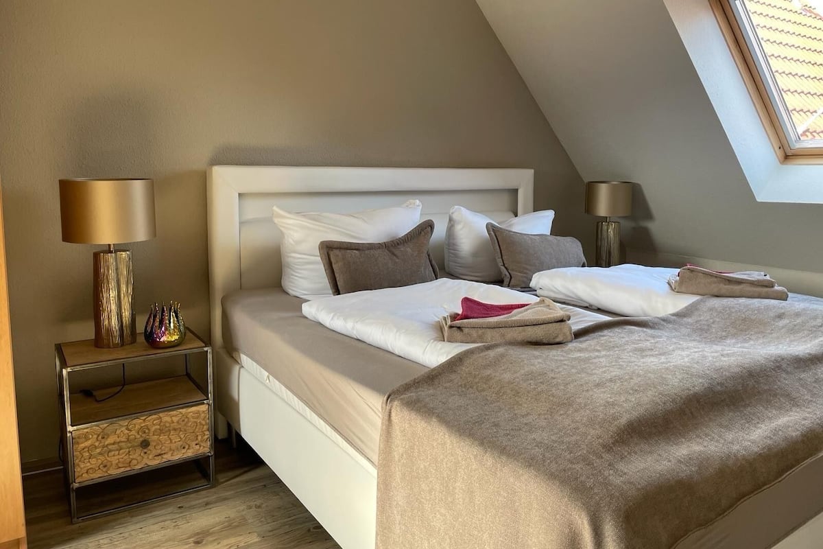 Een keurig opgemaakt slaapkamer met een bed, nachtkastjes en een dakraam.