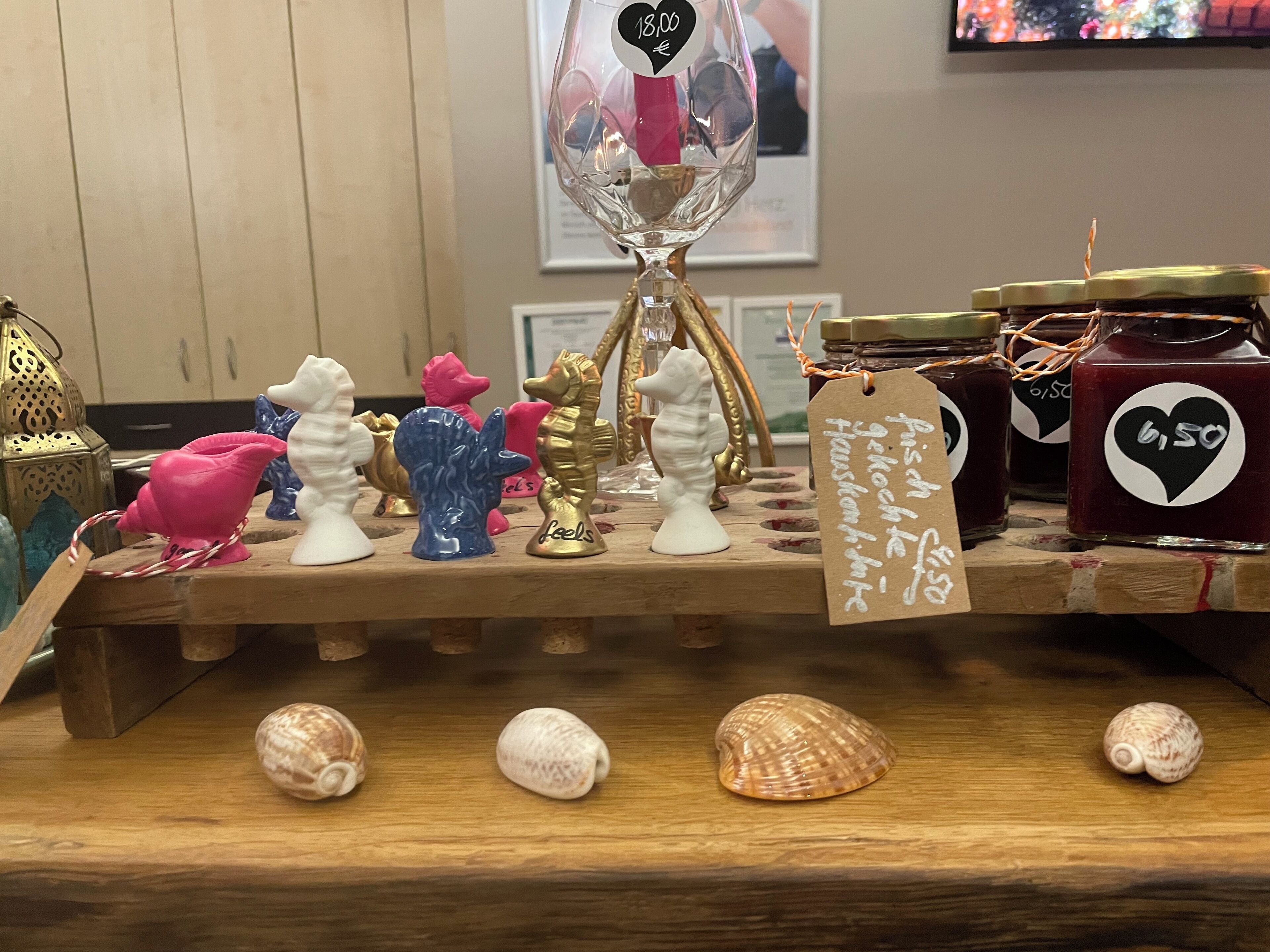 A wooden display with various decorative items including seashells, ceramic figurines, and a glass vase with a price tag.