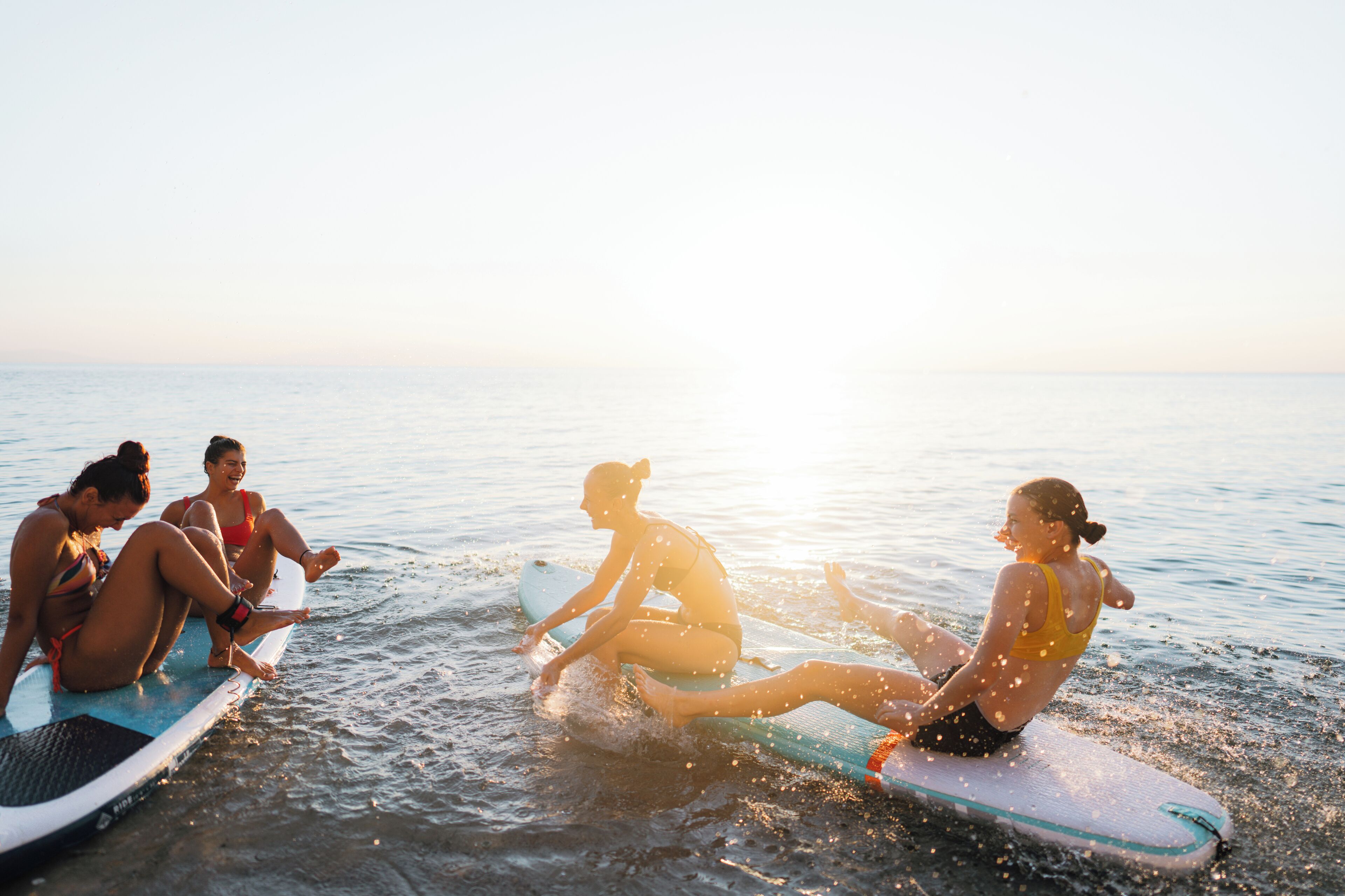 A group of people sitting on surfboards in the water.