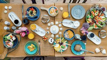 Una mesa de madera con diversos alimentos para el desayuno, incluyendo huevos, tostadas, cereal y una ensalada.