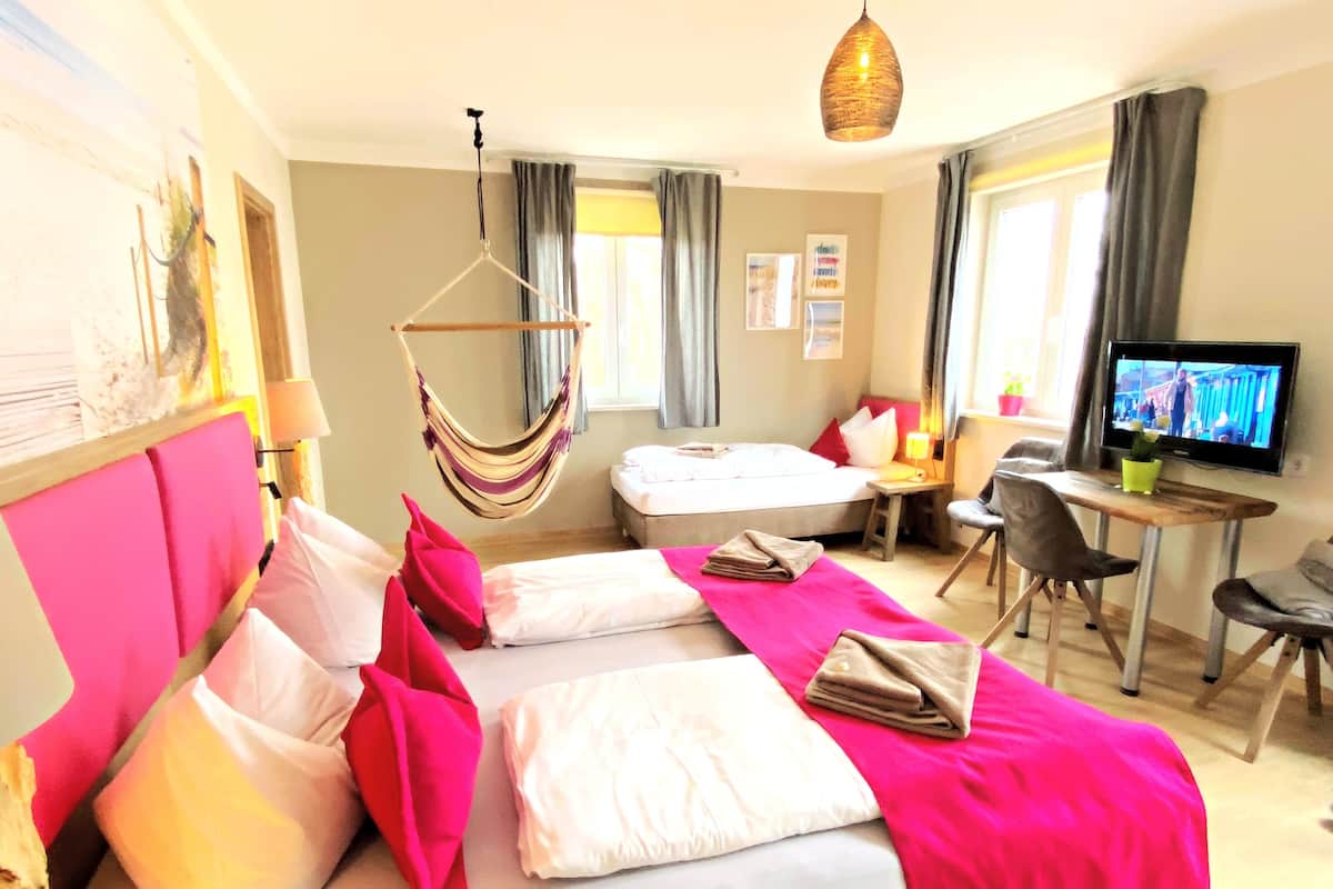 Een hotelkamer met een bed, een bureau, een televisie en een hangstoel.