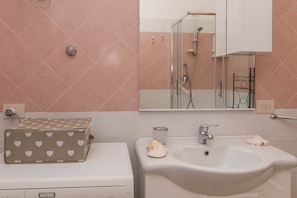 Une salle de bain avec un lavabo, un miroir et une douche.
