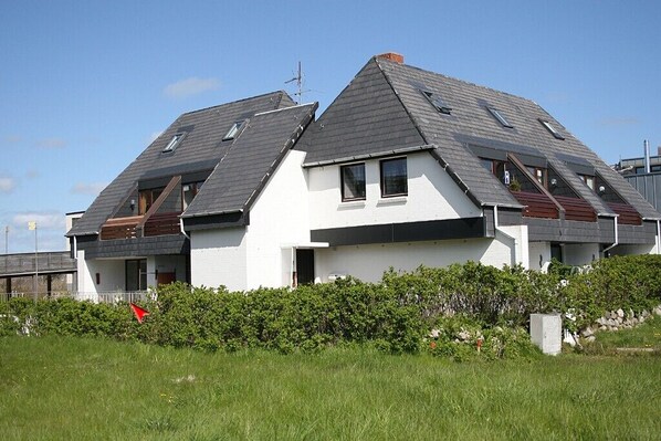 A modern two-story house with a sloped roof, multiple windows, and a white exterior. - This small, cozy one-room apartment in Haus Brigitte... (Hörnum)