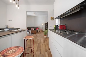 Een moderne keuken met een centraal eiland, een eetruimte met een ronde tafel, en een woonkamer met een bank.