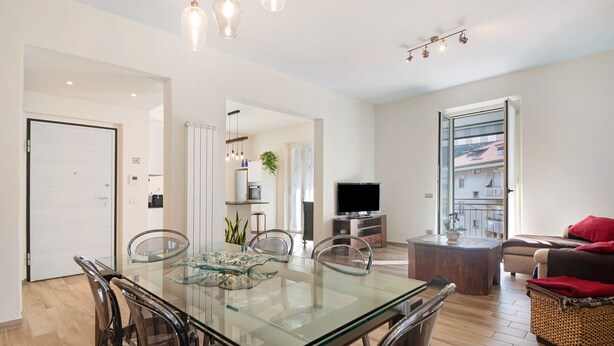 A modern living room with a glass dining table, a sofa, a TV, and a balcony with a view. - Apartment 'Casa Federico ' with Balcony and Wi-Fi (Sestri Levante)