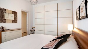 A bedroom with a bed, a dresser, a mirror, a geometric light fixture, and a wall with a grid pattern. - Apartment 'Casa Federico ' with Balcony and Wi-Fi (Sestri Levante)