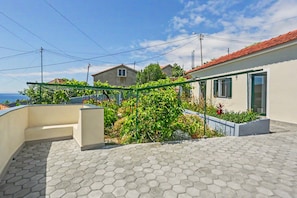 Un quartier résidentiel avec un chemin piétonnier dallé, une rambarde en métal vert et une vue sur des maisons en arrière-plan.