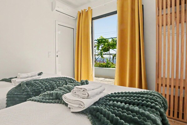 Habitación de hotel con dos camas y vistas a zonas verdes, además de una puerta de listones de madera.