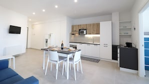 A modern kitchen with white cabinets, a microwave, and a dining area with a table set for four.