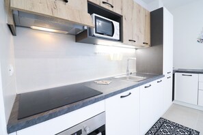 A modern kitchen with a microwave, stove, sink, and wooden cabinets.