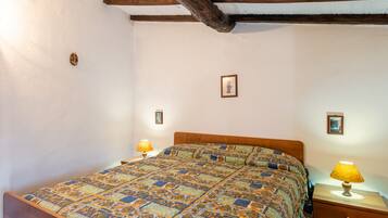 A bedroom with a wooden bed, two bedside tables with lamps, and a ceiling with exposed beams.