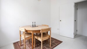 Une pièce avec une table ronde en bois, quatre chaises, un tapis à motifs et une porte blanche.