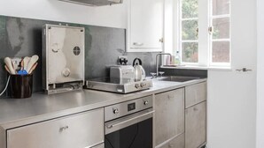 Une cuisine moderne dotée d’appareils électroménagers en acier inoxydable, d’un four encastré et d’une fenêtre donnant sur un paysage verdoyant.