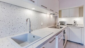 Eine moderne Küche mit weißen Schränken, einer Granit Arbeitsplatte, einer doppelten Spüle und integrierten Geräten.