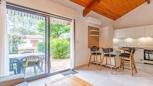 Eine moderne Küche mit weißen Schränken, einer Holzbalkendecke und einem Essbereich mit Tisch und Stühlen.