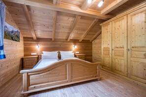 A wooden bedroom with a bed, bedside tables, and a wardrobe.