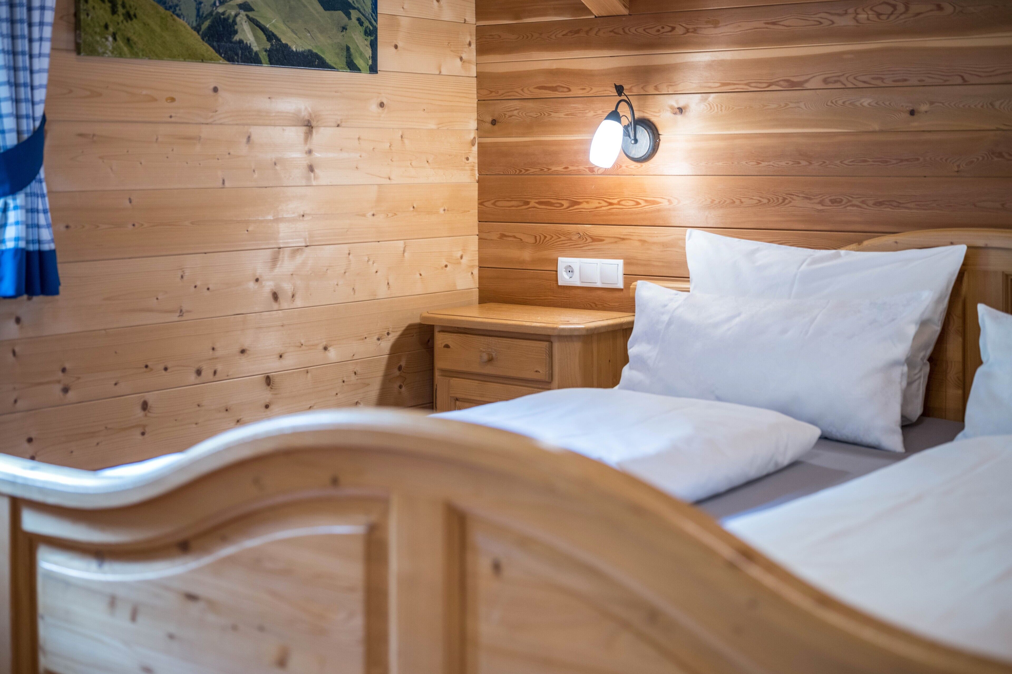 Una camera arredata in stile baita, con un letto, un comodino e una lampada a parete.